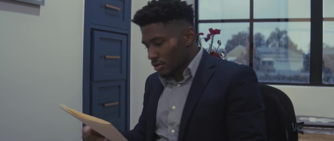 A man sitting in an office takes a folder out of a file cabinet