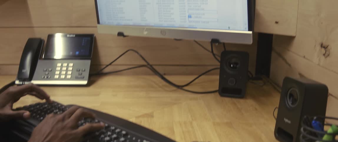 An office employee uses a calculator while typing on a computer keyboard