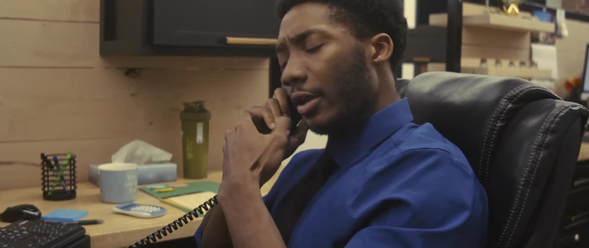 An employee sits in a wooden cubicle while speaking on the phone