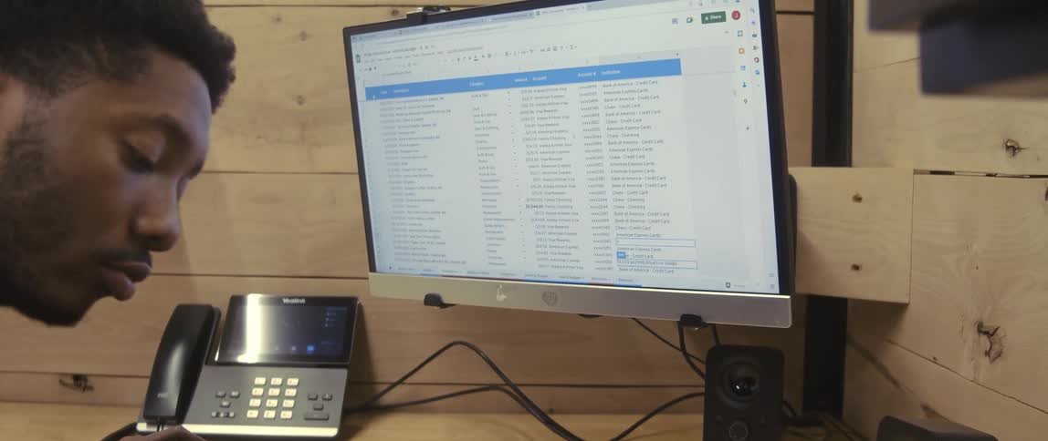 A male employee uses a calculator at his desk near a monitor