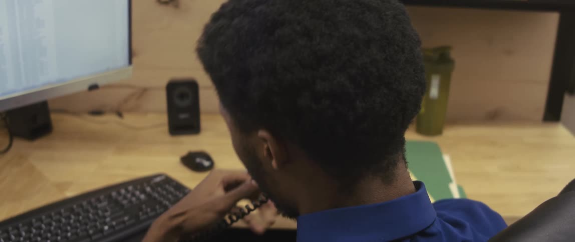 Man sitting at an office desk talking on a phone call