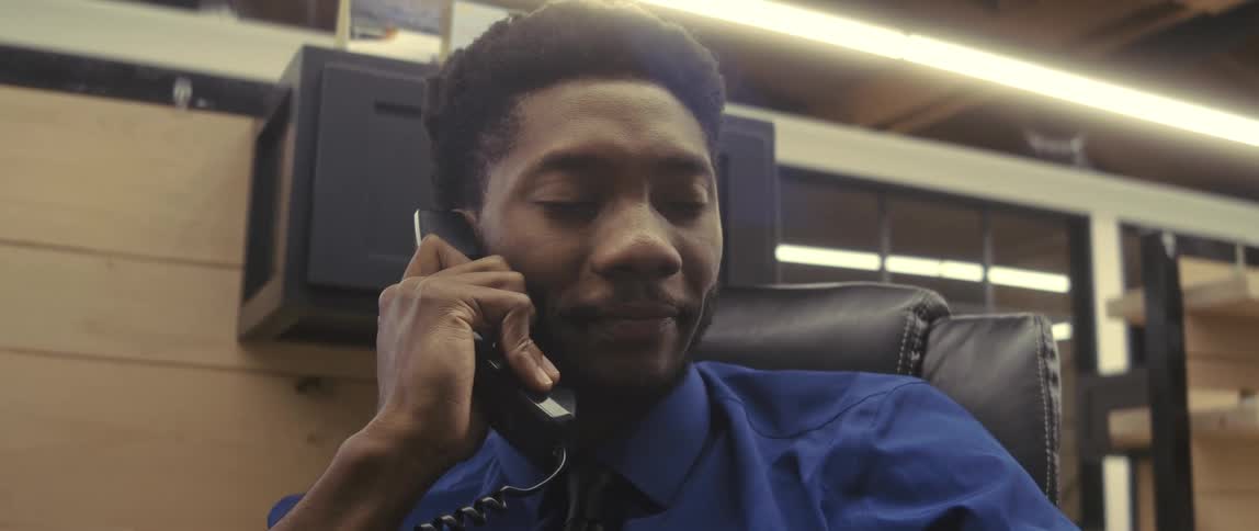 An employee in an office sits in a chair talking on a phone
