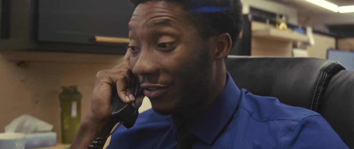 A man in office clothes is sitting and talking on the phone