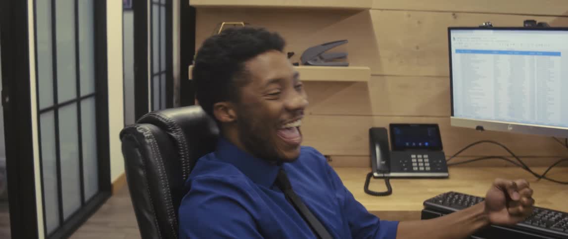 Man sitting at an office desk cheering happily