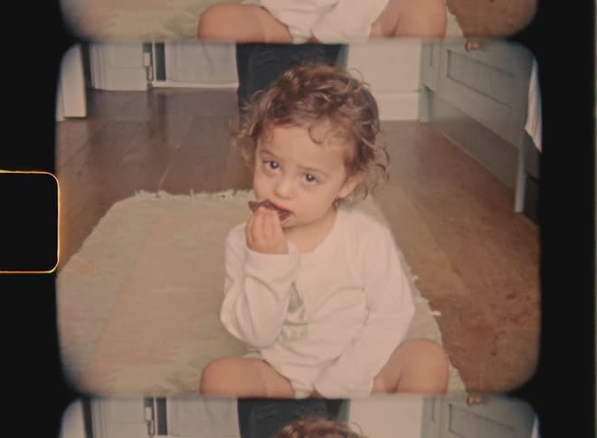 Super 8 film of a baby who is eating a cookie at home on the floor