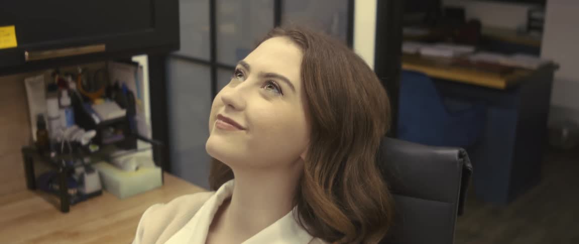 A young woman sitting in her office looking up and feeling relieved