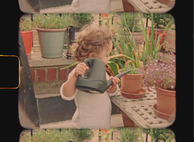 Super 8 footage of a little blonde girl is using a watering can to water the plants that are in pots