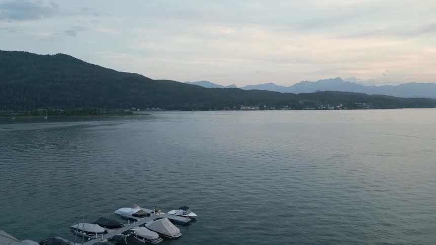 Aerial panorama of boats on a seaside pier with mountains around