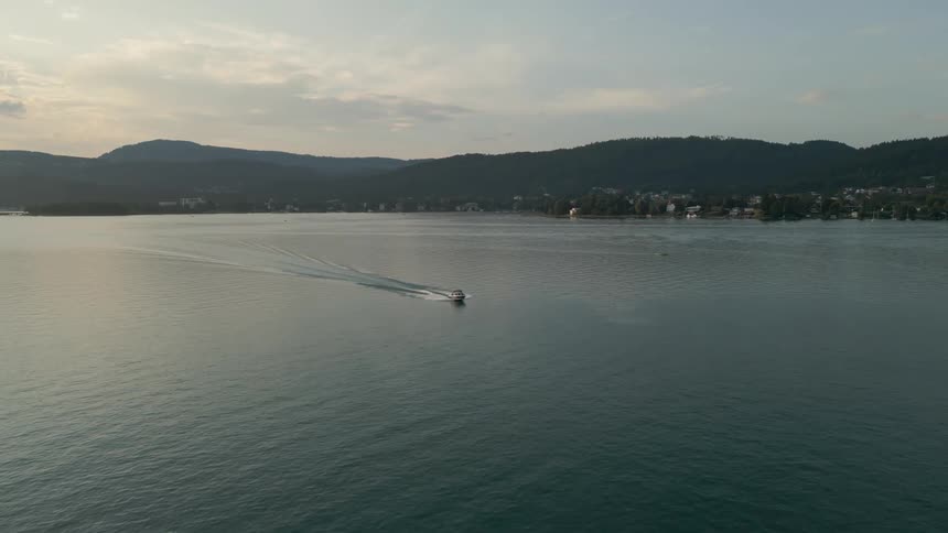 Aerial view of the sea with a small boat passing by and mountains in the distance