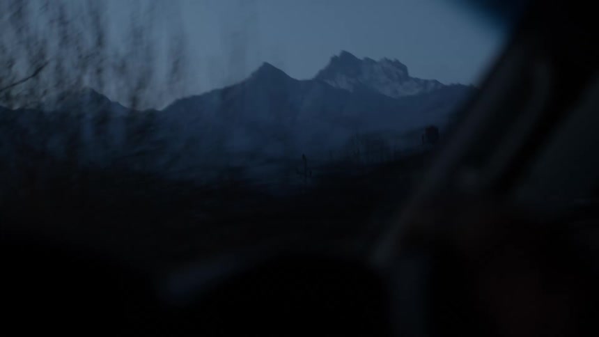 A mountain range is shown from the point of view of a car passenger driving down the road