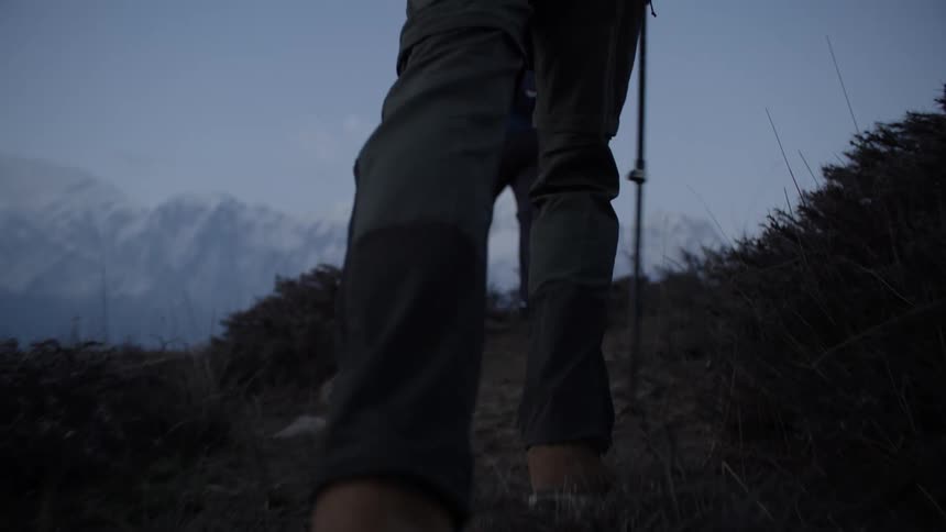 Hikers hold trekking poles as they make their way to the top of a mountain