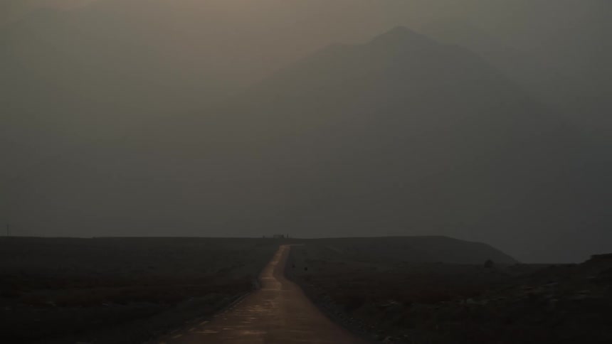 Dirt road street with mountains in the background on a foggy day