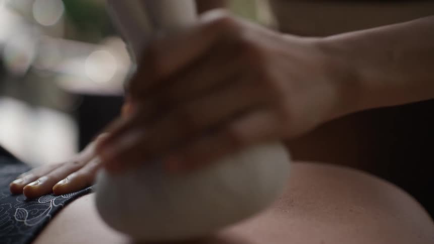 Hand of a person with a white object performing a back massage on another person