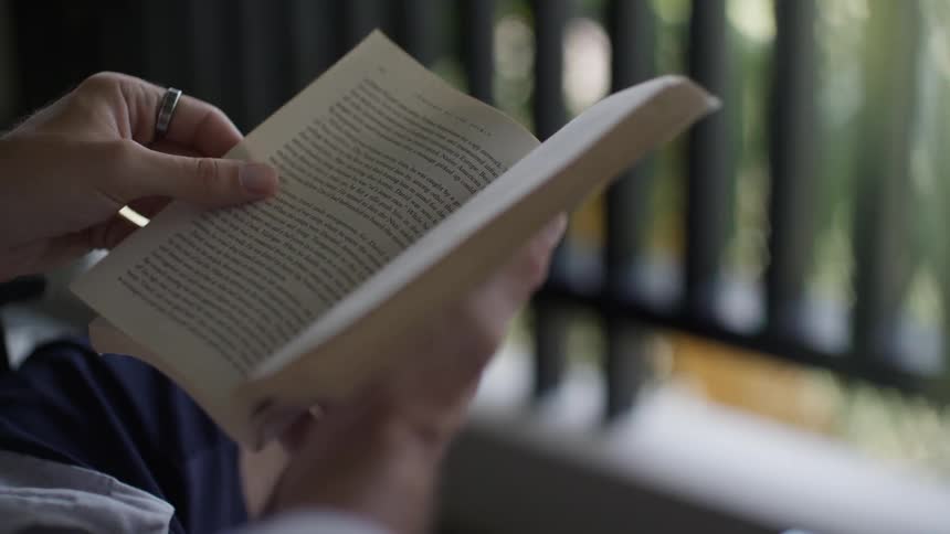 A persons hand holding a book and flipping through the pages with the other hand