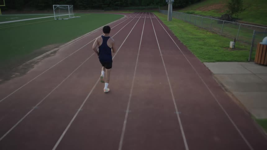 A man runs around a track on a summer day