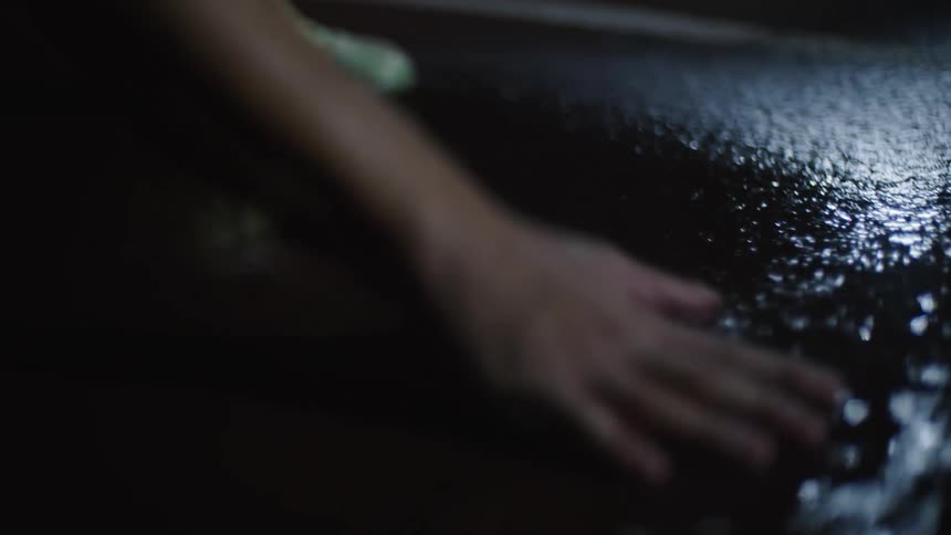 A person slaps their hand against puddles on a asphalt surface