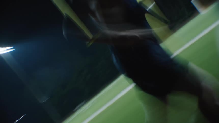 An athlete runs around the edge of a football field at night