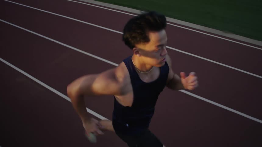 An asian athlete runs on a running track