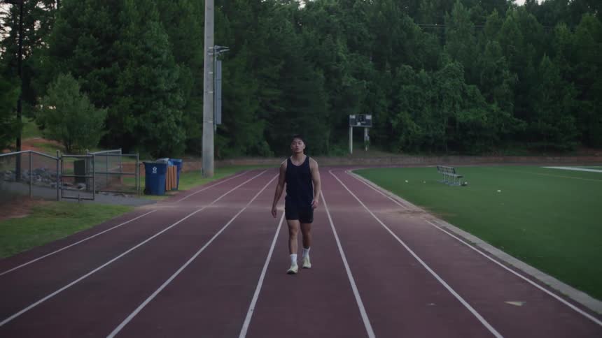 Man in shorts and tank top walking on a running track