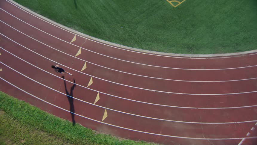 Top view of a person running on an athletics track during the day