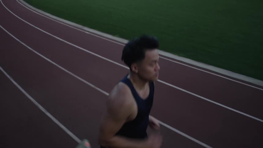 Male athlete jogs along a running track on a summer day