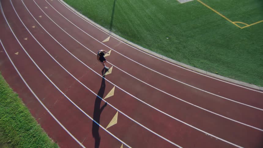 An athlete running on a track with white lane markings and arrows