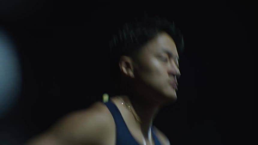 Man wearing a dark blue tank top jogs in the street at night