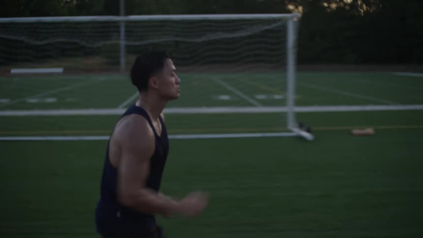 A man running on a running track next to an american football field