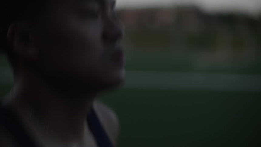 A sweaty athlete running on a track at morning