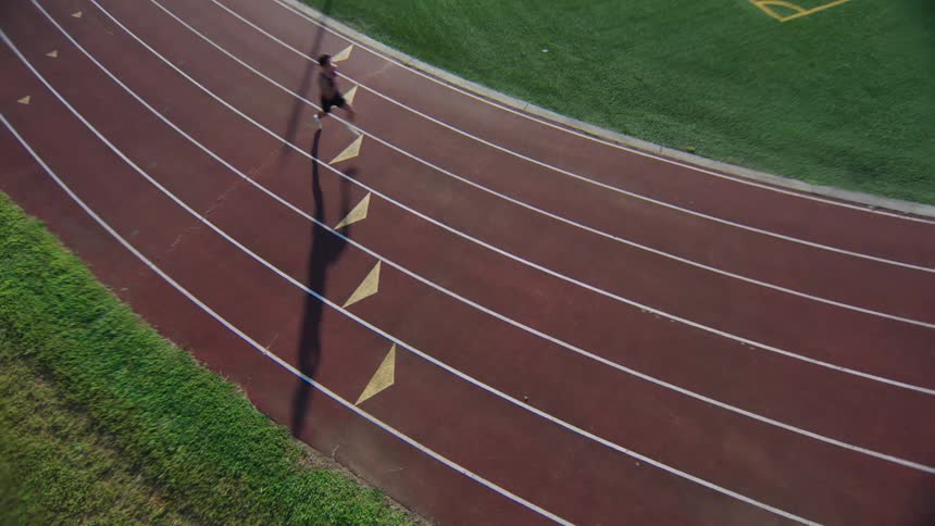 A male runs down a track in a stadium