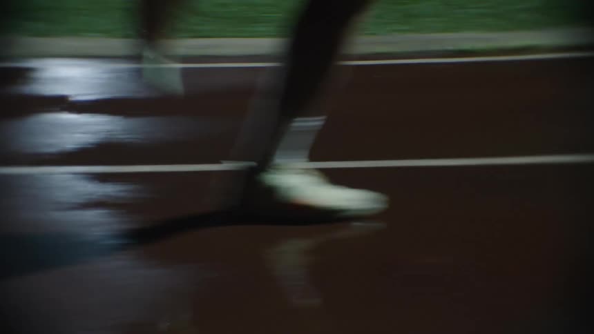 Man running on a wet athletics track at night