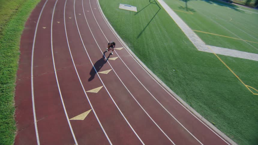 Lone runner takes a starting position on the track and starts running during training