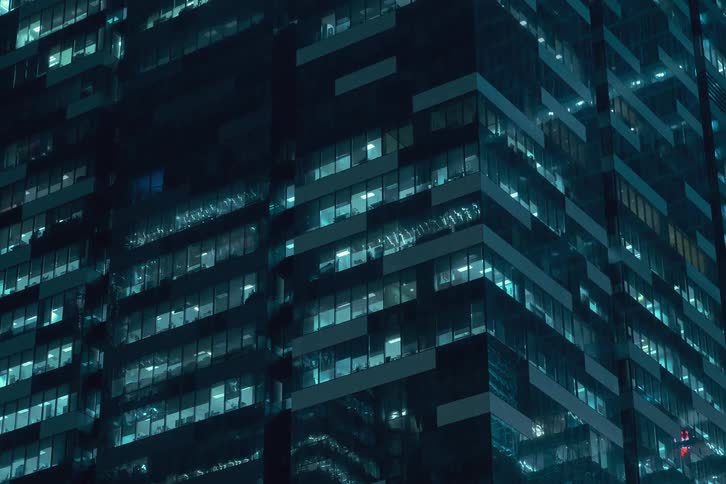 Modern mirrored building with lights turning on and off seen at night