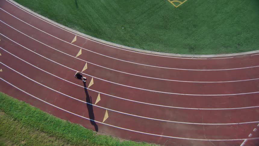 Man entering an athletics track jumping warming up and then running