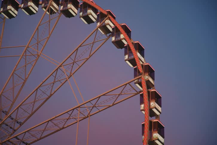 Ferris wheel in motion against a blue sky with shades of pink