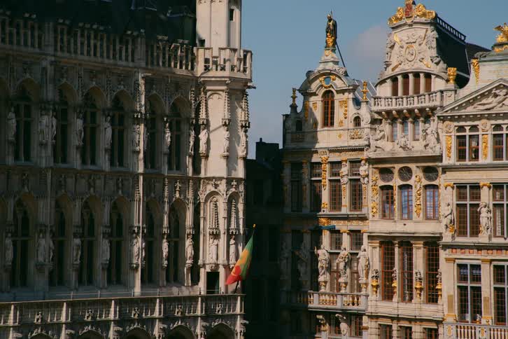 A flag attached to an old building in a city blows in the wind