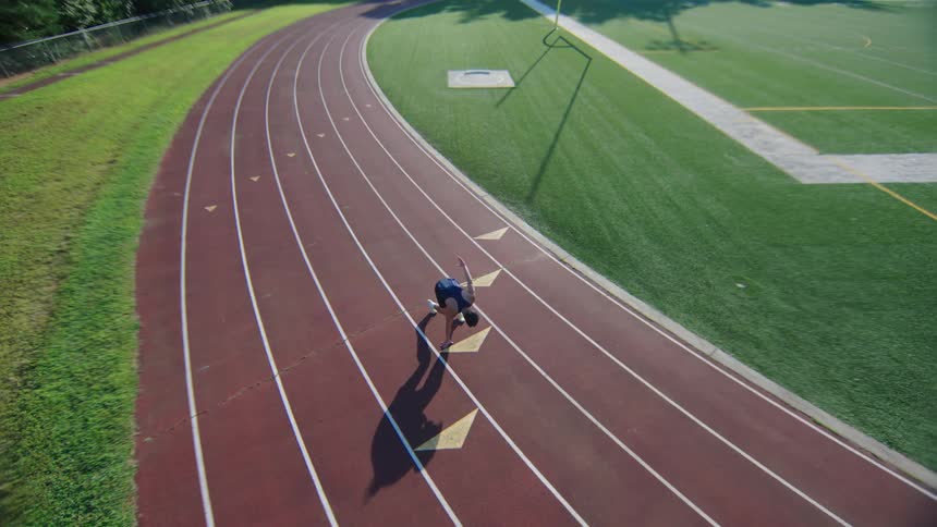 Man getting ready and running at high speed on a running track during the day