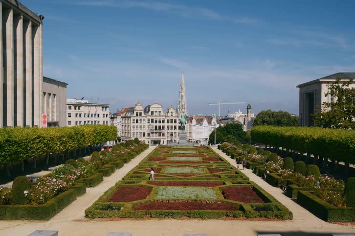 People walk through the landscaped garden between buildings in a coastal town