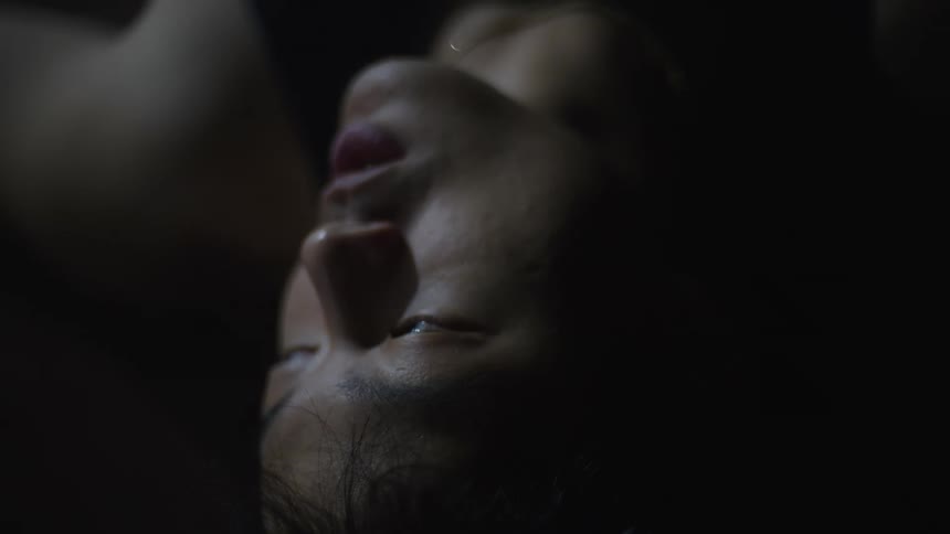 Asian person breathing and turning their head in the dark