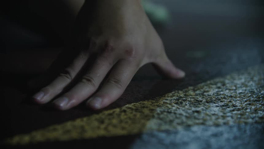 Persons hand positioned on the athletics track at night
