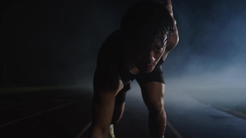 Man gets ready to sprint on a small track in the fog