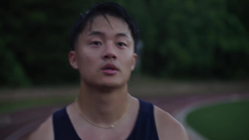 A sweaty asian athlete walks around a track and field track