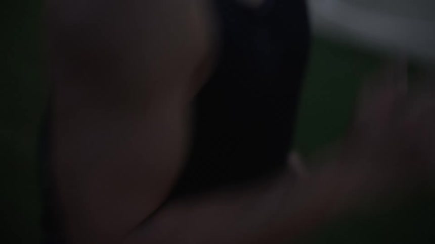 An asian man runs around a track at dusk during the summertime