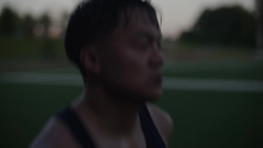 A sweaty athlete running on a track at morning
