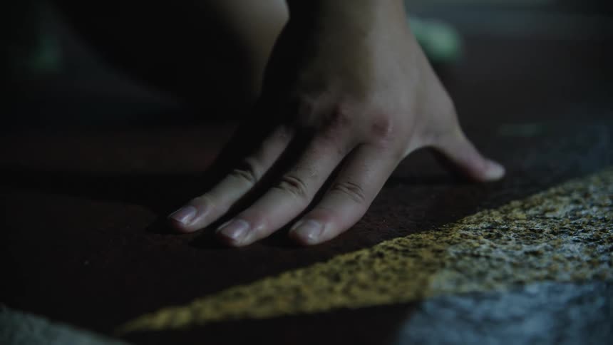 A human hand pressed against a floor painted red with a yellow line
