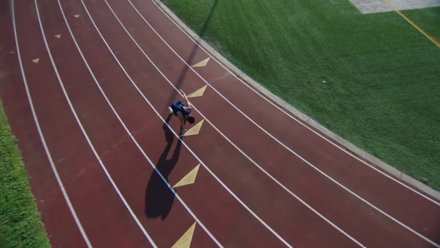 An athlete running on a track with white lane markings and arrows