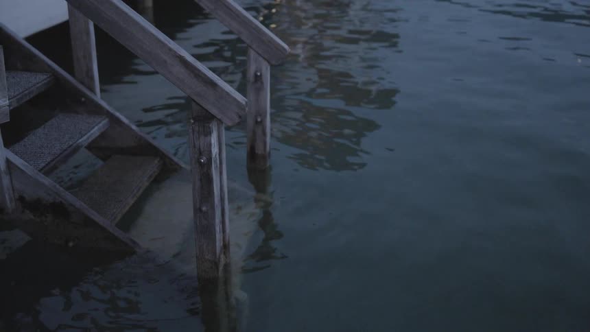 The steps of a wooden staircase leading down to a slowly moving body of water