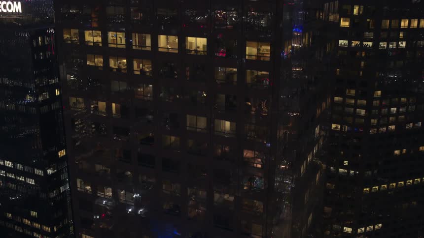 Reflective facade on downtown skyscrapers reflecting the city surroundings at night