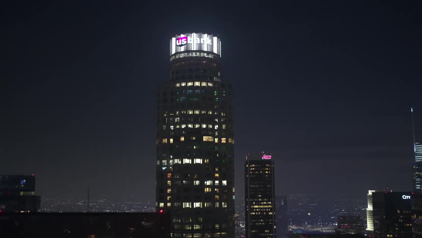 Pulling back to reveal dominating buildings in a large city skyline at night