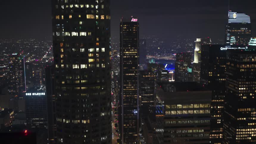 Traffic moves through a downtown area of a vast city at night